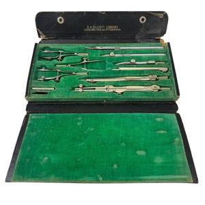 May include: Vintage drafting tools set in a black case with green velvet lining. The case is open, revealing various silver-colored compasses, dividers, and other instruments. The text "B.K. ELLIOTT COMPANY CLEVELAND, OHIO AND PITTSBURGH" is printed on the case.