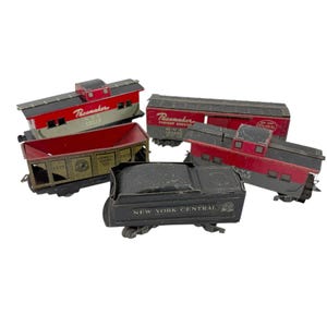 May include: A collection of vintage toy train cars. The cars are painted in red, black, and gray, with some featuring the words "Pacemaker" and "New York Central." The coal car has the words "General Coal Co." and the year "1875."