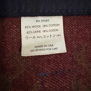 May include: Close-up of a white tag with black text, showing fabric composition and care instructions. The tag reads "RN 29685" and lists the materials as 82% wool and 18% cotton. The tag also states "Made in USA."