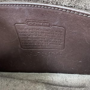 K&ouml;nnte beinhalten: Ein dunkelbrauner Lederaufn&auml;her im Inneren einer Coach-Tasche mit dem gepr&auml;gten Text: THIS IS A COACH BAG. IT WAS HANDCRAFTED IN TURKEY OF COMPLETELY NATURAL GLOVE-TANNED COWHIDE. THE VARIATIONS IN THE GRAIN ARE CHARACTERISTIC OF NATURAL FULL-GRAIN LEATHER. NO L71-9755.