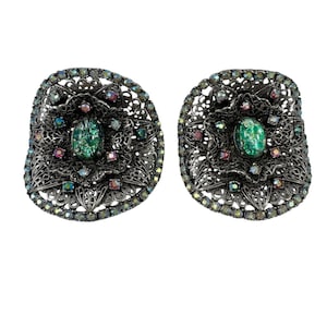 Puede incluir: Un par de pendientes de tono plateado con un diseño de filigrana y piedras iridiscentes verdes y rosas.