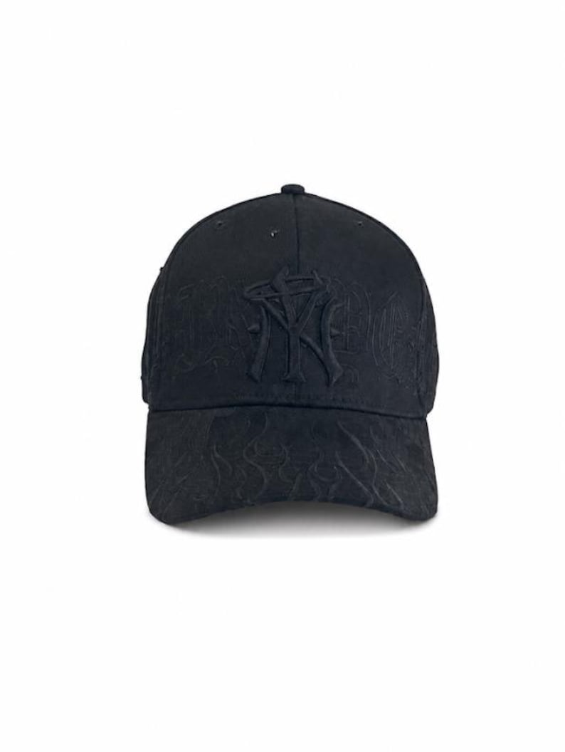 May include: A black baseball cap featuring a tonal embroidered NY logo on the front panel. The cap is decorated with a subtle, matching black flame-like pattern embossed across the crown and the curved brim, creating a monochromatic look.