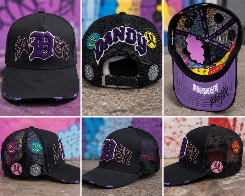 May include: A black trucker hat featuring purple embroidered text that reads "BADBOY" and "DANDY," accented with colorful circular patches depicting various facial expressions. The hat includes a mesh back, a distressed brim, and interior lining.