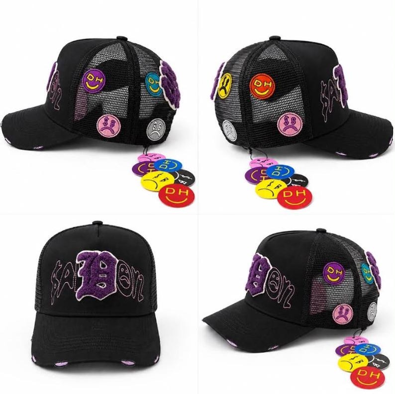 May include: A black trucker hat featuring a mesh back and a curved brim with distressed details. The front displays purple embroidered text, while the sides and a dangling attachment are decorated with various colorful circular patches.