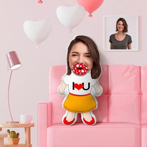 May include: A custom-shaped throw pillow featuring a photographic print of a person's face with exaggerated red and white polka-dot lips, wearing a white t-shirt with the text I heart U and a yellow skirt with red shoes.