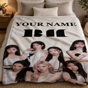Puede incluir: Una manta de forro polar color crema con el texto "YOUR NAME" en letras mayúsculas negras sobre un gráfico negro grande. Debajo, un collage de seis jóvenes con cabello largo oscuro y claro que visten blusas blancas impreso en la tela.