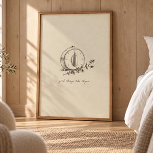 Puede incluir: Una lámina enmarcada con un dibujo lineal en blanco y negro de un temporizador de cocina y una ramita de tomillo. Debajo de la ilustración, el texto good things take thyme aparece en una fuente sencilla, minúscula y manuscrita.
