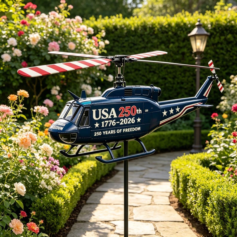 May include: A dark blue metal helicopter garden spinner featuring red and white striped rotor blades. The fuselage displays the text USA 250th 1776-2026 and 250 YEARS OF FREEDOM with white stars. The helicopter is mounted on a black metal pole.