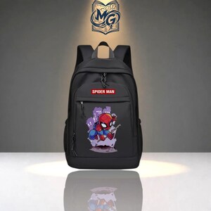 Puede incluir: Una mochila negra con un parche rectangular rojo con el texto blanco SPIDER MAN. El bolsillo delantero muestra un gr&aacute;fico de un personaje de Spider-Man en un traje rojo y azul sobre un fondo de silueta de ciudad de color morado.