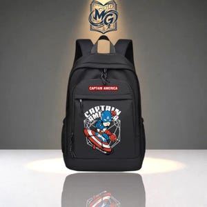 May include: A black backpack featuring a graphic of Captain America with a shield on the front pocket. The text CAPTAIN AMERICA is printed in white on a red rectangular background above the graphic. A logo with the letters MG is at the top.