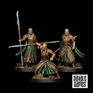 Peut inclure: Trois figurines miniatures de guerriers elfes en armure dorée et capes vertes, tenant chacune une longue lance. Les personnages sont dans des postures de combat sur des socles circulaires. Le texte "DAVALE GAMES" est inscrit dans un carré blanc.