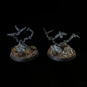Könnte beinhalten: Zwei Miniatur-Spielfiguren, die dunkelgraue Vögel im Flug darstellen und auf runden Sockeln montiert sind. Die Sockel sind mit strukturiertem Boden, kleinen Steinen, verstreuten Knochenfragmenten und getrockneten Pflanzendetails verziert.