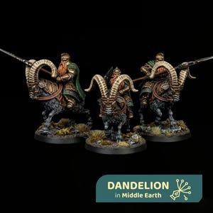 Puede incluir: Tres figuras en miniatura de guerreros con armadura y largas barbas montando grandes carneros con cuernos curvados. Los jinetes llevan armaduras de bronce metálico y capas verdes, sosteniendo lanzas. El texto DANDELION in Middle Earth es visible abajo.