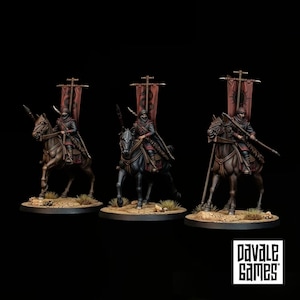 Puede incluir: Tres figuras en miniatura de guerreros montados a caballo, cada una con un estandarte rojo alto con un emblema negro. Los jinetes visten capas oscuras con capucha y armaduras, sosteniendo lanzas sobre caballos marrones y negros en bases.