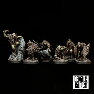 Könnte beinhalten: Ein Set aus sechs bemalten Goblin-Miniaturen in verschiedenen Kampfposen, mit grüner Haut, brauner fellbesetzter Rüstung und metallischen Waffen. Einige Figuren tragen große segmentierte Schilde, andere halten geschwungene Klingen. Pavale Games Logo enthalten.