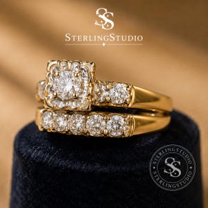 Puede incluir: Un conjunto de anillos de oro que incluye un anillo de compromiso con un diseño cuadrado y una alianza a juego. Ambas piezas están adornadas con múltiples diamantes blancos redondos de talla brillante. El texto SterlingStudio es visible.
