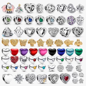 Puede incluir: Una colección de dijes de metal en tonos plateados y dorados con diversas formas, incluyendo corazones, animales, estrellas y flores. Muchos dijes cuentan con piedras preciosas de colores, detalles en esmalte o patrones de filigrana intrincados.