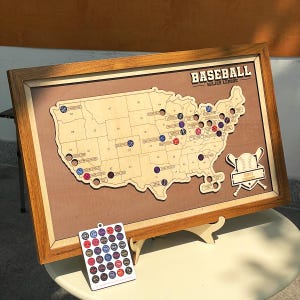 May include: A framed wooden map of the United States featuring baseball stadium locations marked with circular cutouts. The text BASEBALL MAJOR LEAGUE is at the top right. A separate rectangular card displays various team logos in a grid pattern.