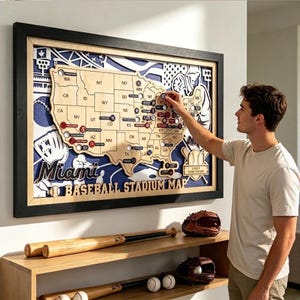 May include: A framed wooden map of the United States featuring baseball stadium locations, with the text Miami Baseball Stadium Map. The map includes cutouts for circular tokens, layered blue and white background graphics of baseball gear.
