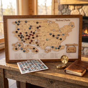 May include: A wooden framed map of the United States featuring National Parks, with circular cutouts for tokens. Includes a separate sheet of park tokens, a brass compass, and a leather-bound journal. The map displays the text National Parks.