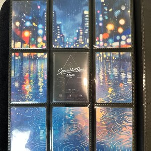 May include: A black trading card binder page containing nine slots. Eight slots feature cards with a rainy city night scene with colorful bokeh lights and water ripples. The center card is black with the white text Special Art Rare A SAR.