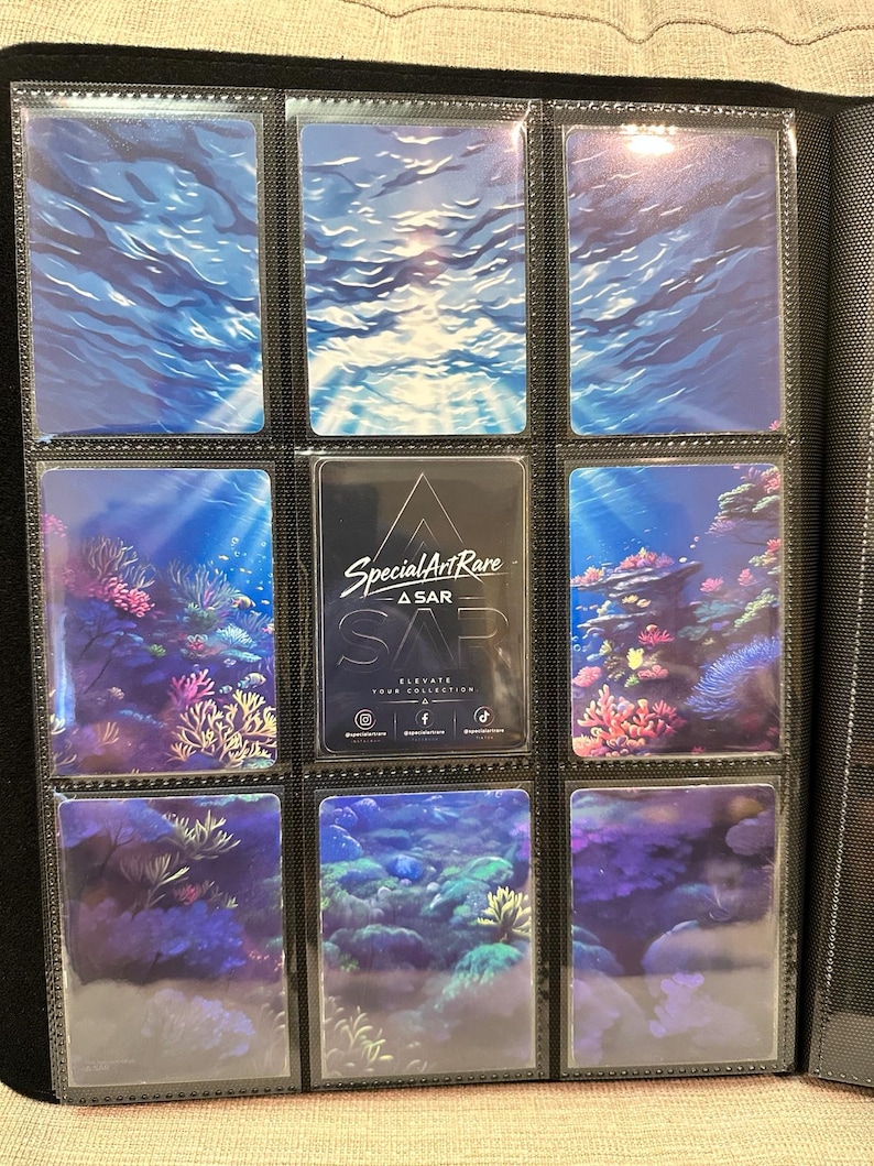 May include: A black trading card binder page containing nine rectangular cards. The top row shows blue water surfaces. The middle row features coral reefs and a central black card with the text Special Art Rare, ASAR, SAP, and social media icons.