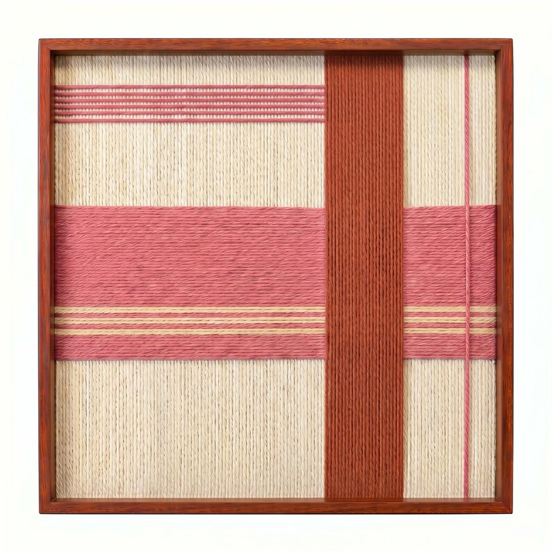 May include: A square, woven textile art piece in a wooden frame. The design features a cream-colored background with horizontal and vertical bands of pink and rust-colored yarn. The frame is a warm, medium brown.