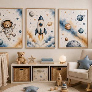 May include: Three framed wall art prints featuring watercolour-style space themes. The left print shows a bear in an astronaut suit, the centre print depicts a rocket ship launching, and the right print displays various planets and stars in blue and gold.