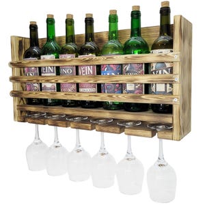 Peut inclure: Un casier à vin mural en bois brûlé doté de trois lattes horizontales pour maintenir sept bouteilles de vin en verre vert avec des bouchons en liège. Sous les bouteilles, une étagère en bois à six fentes supporte six verres à pied à l'envers.