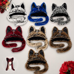 May include: A collection of seven plush faux fur hats featuring cat ears, each adorned with a silver-toned cross emblem and a delicate chain detail. The hats are available in various colors including white, blue, black, red, tan, and brown patterns.