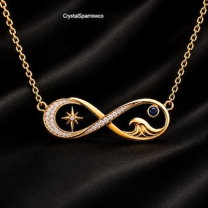 Pode incluir: Um colar com pingente de infinito em tom dourado, apresentando um design de estrela de um lado e um motivo de onda com uma pequena pedra azul do outro. O pingente é adornado com cristais claros e suspenso por uma corrente dourada fina. Texto: CrystalSparrowco.