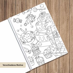 May include: A spiral-bound coloring book page featuring black and white line art of various desserts including a tiered cake, cupcakes, ice cream, and candies, with the text Verschiedene Motive printed in a small box at the bottom left corner.