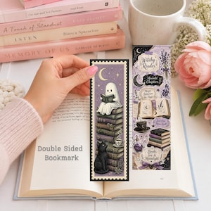 May include: A double-sided bookmark featuring a purple and cream colour palette. One side shows a ghost reading on a stack of books with a black cat. The other side displays illustrations of books, a teacup, a potion bottle, and text including Witchy Reader.