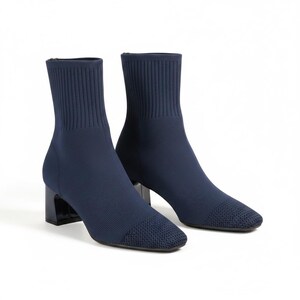May include: A pair of navy blue ankle boots featuring a ribbed knit shaft, a square toe with a textured knit cap, and a solid block heel. The boots are constructed from a flexible fabric material that extends from the ankle to the toe area.