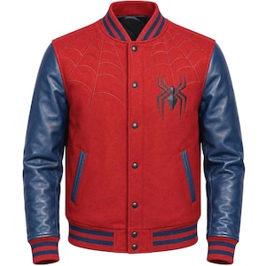 Puede incluir: Una chaqueta universitaria roja con mangas de cuero azul y cuello, puños y dobladillo acanalados con rayas azules. El torso rojo muestra un emblema de araña negro en el pecho y un patrón de telaraña cosido en los paneles frontales.