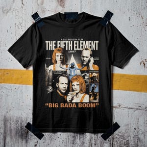 Puede incluir: Una camiseta negra de manga corta con un estampado gráfico de la película El quinto elemento de 1997. El diseño incluye retratos de Leeloo y Korben Dallas, imágenes de la película y el texto A Luc Besson Film, The Fifth Element, 1997 y Big Bada Boom.