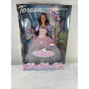 以下が含まれることがあります： 「Barbie of Swan Lake」のFairy QueenとしてのTeresa人形。箱入り。長い茶色の髪、透明な層のあるピンクと紫のガウンを着用し、紫色の笏を持っています。パッケージには城のイラストが描かれています。