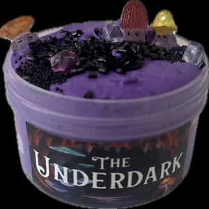 May include: A container of purple slime with decorative elements. The slime is topped with black sprinkles, clear and pink gem-like pieces, and mushroom-shaped charms. The container has a label with the text "The Underdark" in a stylized font.