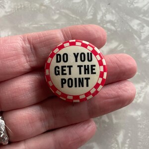May include: A white button with a red and white checkered border. The button says "Do you get the point" in black text.