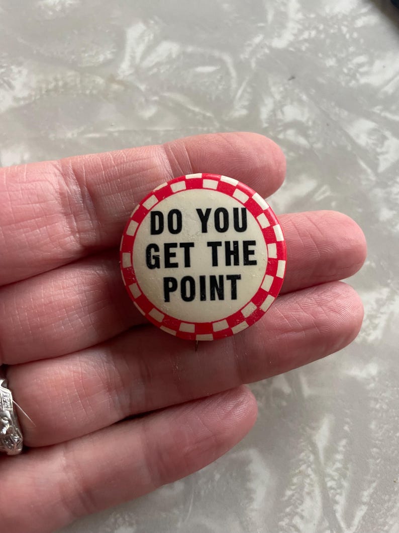 May include: A white button with a red and white checkered border. The button says "Do you get the point" in black text.