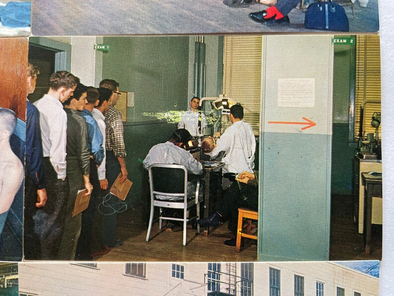 May include: A group of men stand in a line in a room with a dental exam room in the background. The room has a light blue wall with the words "Exam 2" written on it. The dental exam room has a dental chair and a dentist in a white coat.