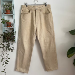 May include: A pair of light beige, straight-leg jeans with a high waist and five pockets.
