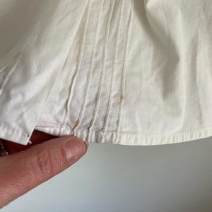 Puede incluir: Primer plano de una tela de algod&oacute;n blanca con pliegues y algunas peque&ntilde;as manchas marrones.