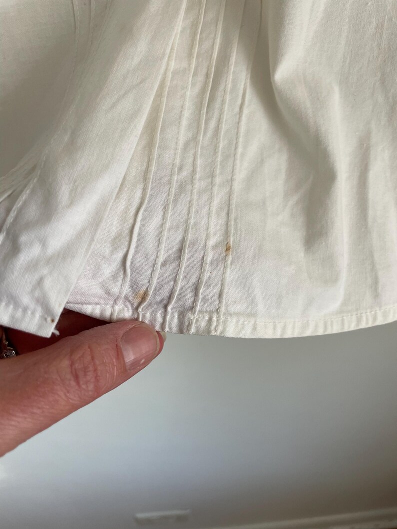 Puede incluir: Primer plano de una tela de algod&oacute;n blanca con pliegues y algunas peque&ntilde;as manchas marrones.