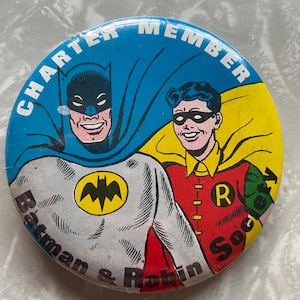 May include: A blue, yellow, and red round button with a picture of Batman and Robin. The text on the button reads "Charter Member Batman & Robin Society".
