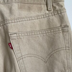 May include: A pair of beige denim jeans with a red Levi's patch on the back pocket.