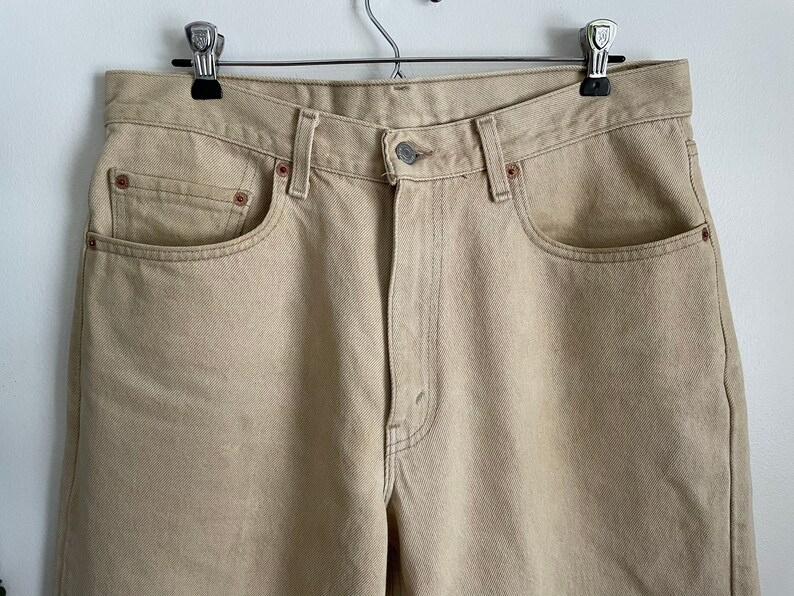 May include: A pair of light beige denim jeans with a classic five-pocket style.