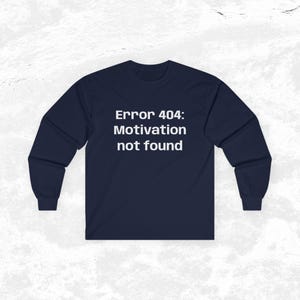 Op de afbeelding: Een marineblauw shirt met lange mouwen en de witte tekst "Error 404: Motivation not found" in het midden op de borst. Het kledingstuk heeft een ronde hals en lange mouwen met geribbelde boorden, wat zorgt voor een eenvoudig ontwerp.