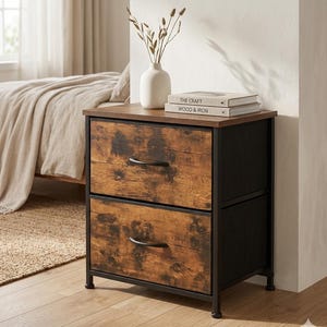 May include: A two-drawer nightstand with a dark wood-grain finish on the drawer fronts, a black metal frame, and a brown top surface. Two books titled The Craft and Wood & Iron are stacked on top, next to a white vase with dried stems.