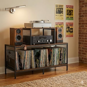 Puede incluir: Una consola de discos de madera y metal con un tocadiscos, amplificador y altavoces. La consola contiene numerosos discos de vinilo. Hay carteles vintage en la pared. Una lámpara de pared está encima de la consola.